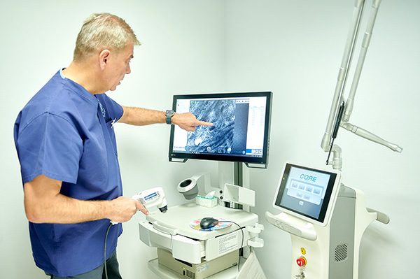 Dermatólogo revisando imágenes de dermatoscopia digital en la consulta